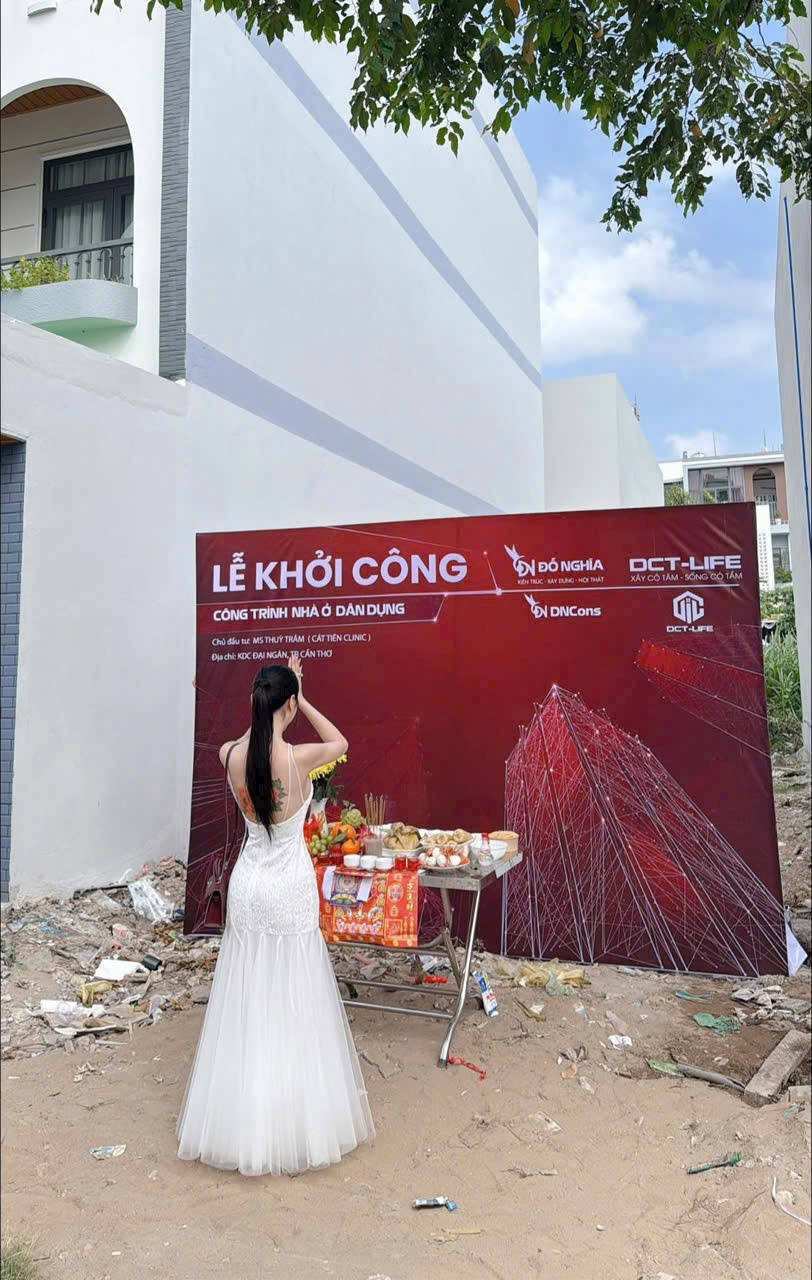 Bếp hiện đại, phòng ăn liền kề, tủ bếp màu trắng, đảo bếp mặt đá vân mây trắng, bồn rửa, ghế bar đen, bàn ăn gỗ hình chữ nhật, ghế ăn bọc nệm be, đèn thả trần, cửa sổ, sàn gạch sáng.